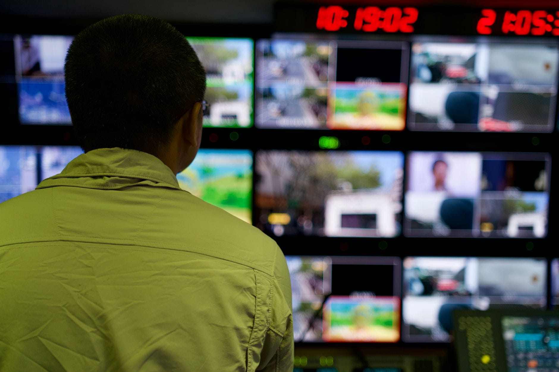 Operator w centrum monitoringu obserwuje wiele ekranów z nagraniami